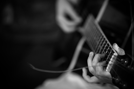 Closeup of man's hands playing guitar on the concert. Guitarist. Monochrome. Music concept