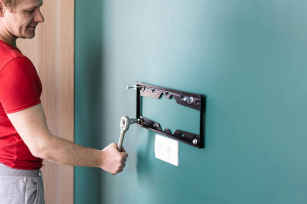 reparación y decoración. servicio de "esposo por una hora". un hombre fija un soporte de tv a una pared. - wall mount fotografías e imágenes de stock