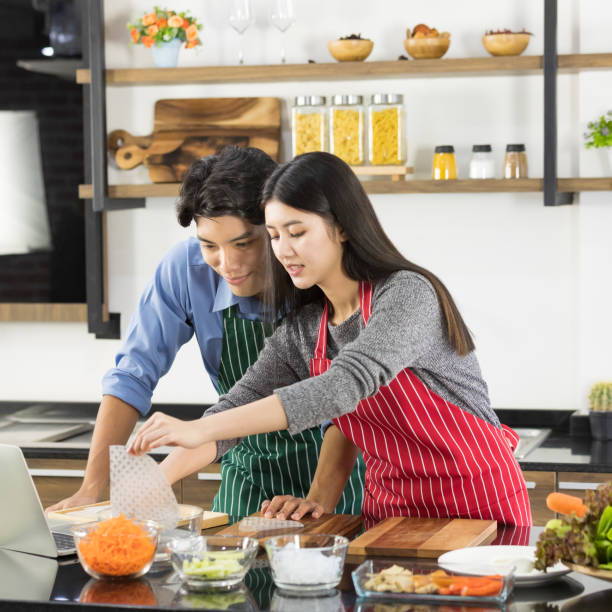 istock Asian couple in apron make a salad together. 1221783140