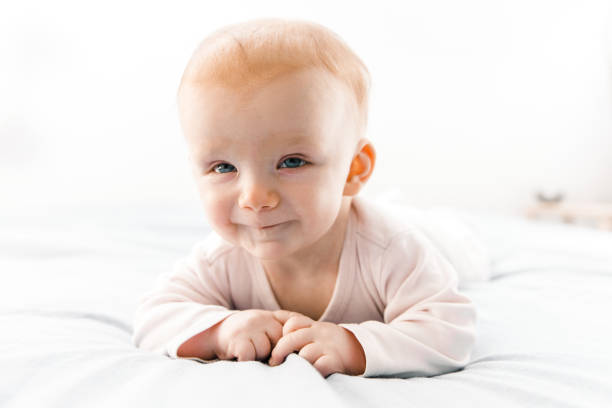 istock Joyful smiling red haired baby girl crawling on bed sheet 1221784589