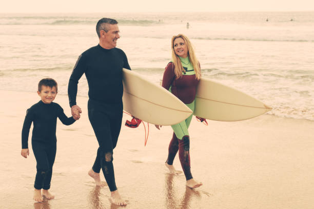 istock Happy family with surfboards walking on beach 1221785453