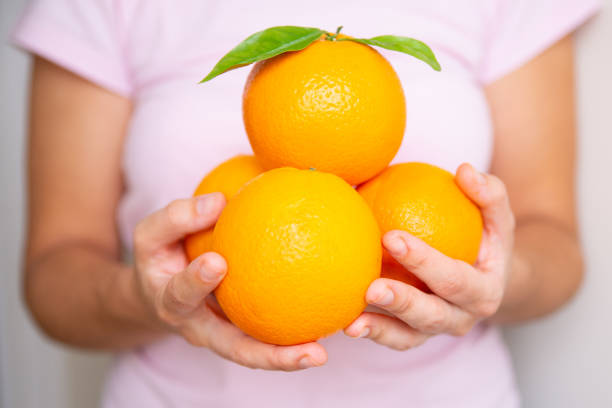 istock Lady in pink shirt holding four oranges 1221786101