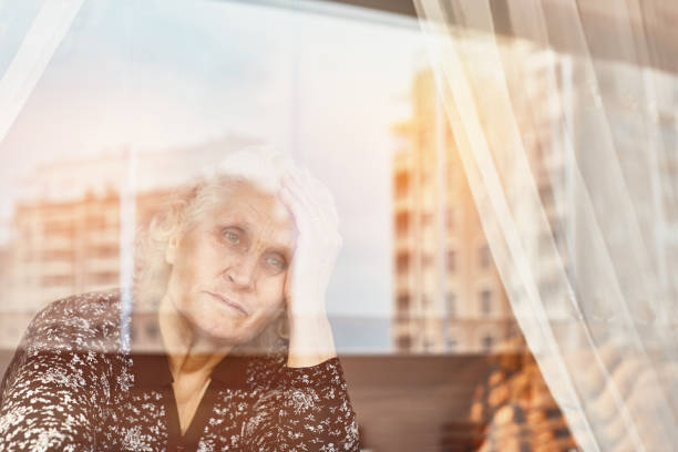 istock Elderly woman sitting alone and looking sadly outside the window 1221787919