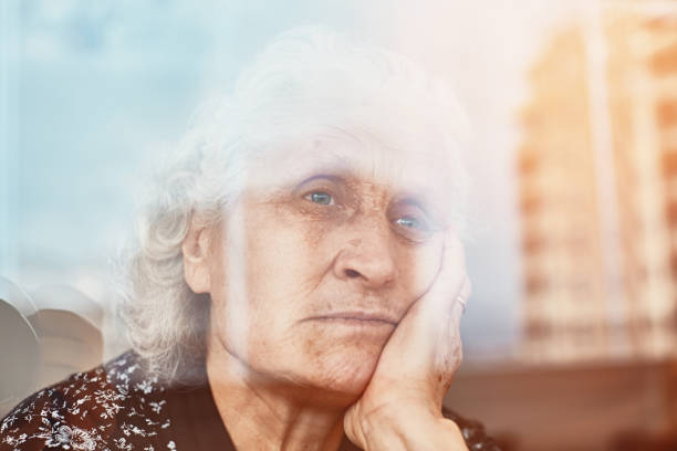 istock Elderly woman sitting alone and looking sadly outside the window 1221787945