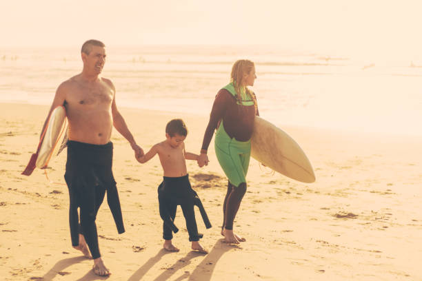 istock Cheerful family with surfboards walking on ocean coast 1221788139