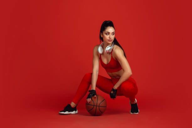istock Beautiful young female athlete practicing on red studio background, monochrome portrait 1221789919