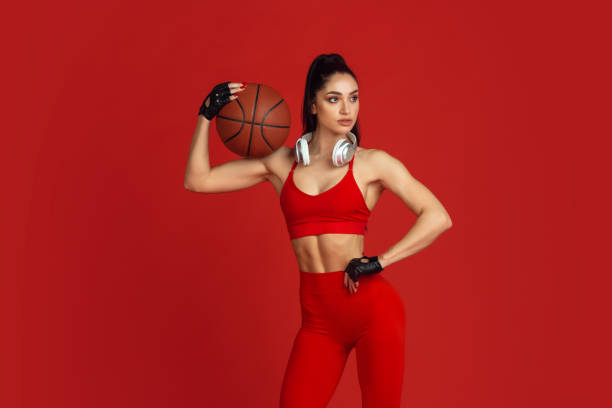 istock Beautiful young female athlete practicing on red studio background, monochrome portrait 1221789922