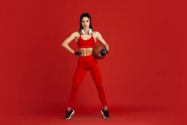 istock Beautiful young female athlete practicing on red studio background, monochrome portrait 1221789926