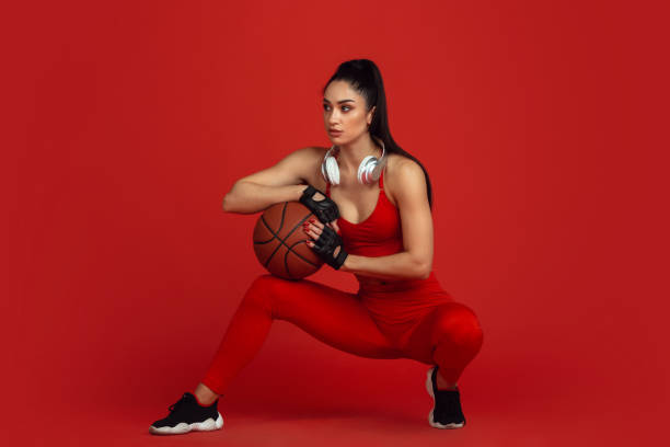 istock Beautiful young female athlete practicing on red studio background, monochrome portrait 1221789927