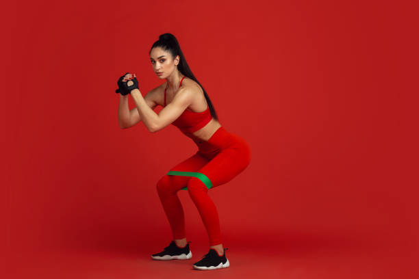 istock Beautiful young female athlete practicing on red studio background, monochrome portrait 1221789938