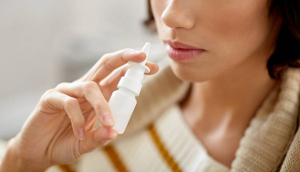 close up of sick woman using nasal spray