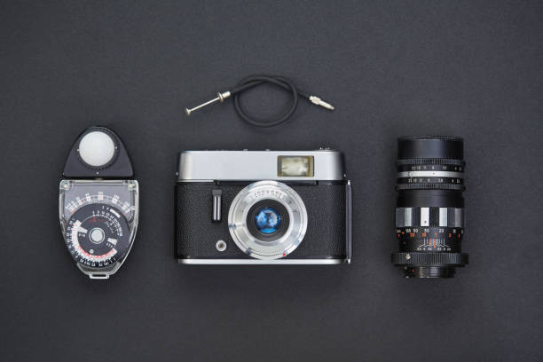 istock Front view of a vintage analog film camera, lens, cable release and lightmeter on black background 1221792320