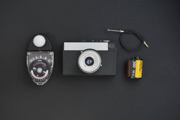 istock Front view of a vintage analog film camera, lens, cable release and lightmeter on black background 1221792359