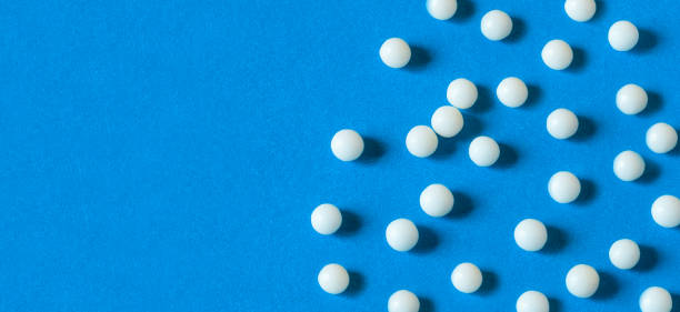 istock White medical pills on blue background. 1221793980