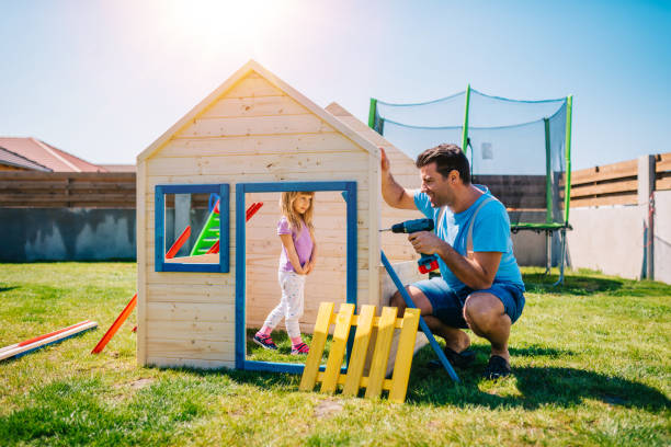 Father and daughter building a wooden house together Father assembling wooden house for his daughter at home playground back yard kids play house stock pictures, royalty-free photos & images