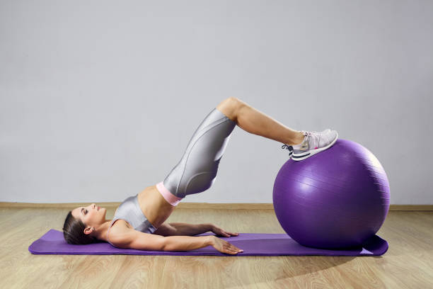 jeune femme d’ajustement faisant l’exercice dans une gymnastique. la fille de sport s’entraîne en forme croisée avec des boules de pilates. - yoga ball photos et images de collection