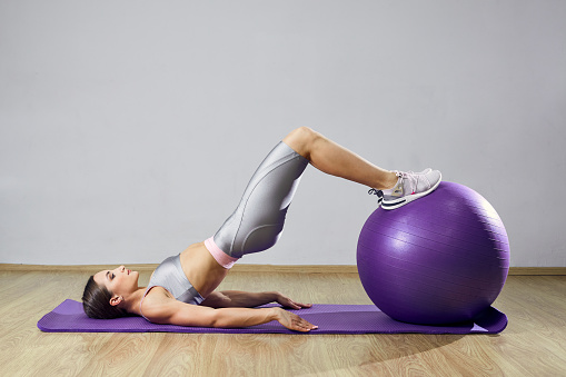 Young fit woman exercising in a gym. Sports girl is training cross fitness with a Pilates Balls.