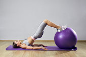 Young fit woman exercising in a gym. Sports girl is training cross fitness with Pilates Balls.