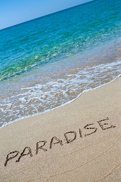 Paradise written on the sand stock photo