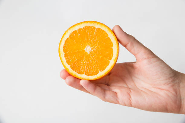 istock Unrecognizable person showing cut half of orange 1221795848