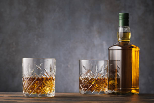 istock Two glass with whiskey and alcohol bottle on dark background 1221797537