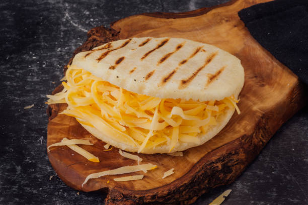 Arepa with yellow cheese on a wooden board. (Arepa Catira) stock photo