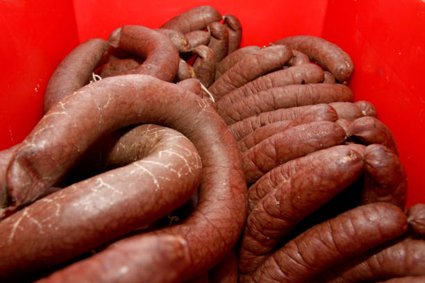 istock A worker at the meat processing factory, prepares sausages at the work table. Food processing and processing industry. Raw meat mix: steaks, poultry, sausages, ham, chopped, minced meat. The farm. Unique home production 1221798889