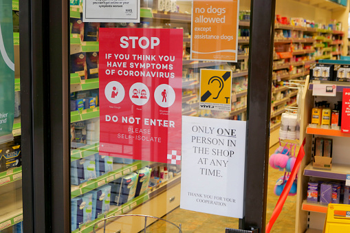 17th April 2020: View of a town centre pharmacy window in Penicuik in Midlothian, Scotland. The pharmacy has a one person at a time social distancing policy, during the Coronavirus pandemic, to protect staff who are serving numerous customers coming for their prepared prescriptions and other medical items. Posters on the door outside inform customers of their entrance policy.