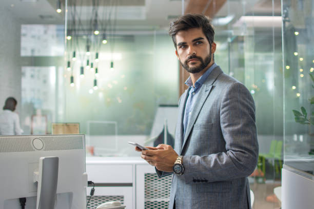 istock Young handsome businessman using phone in the office. 1221799362