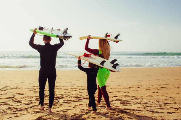 istock Family with surfboards walking on beach 1221800066