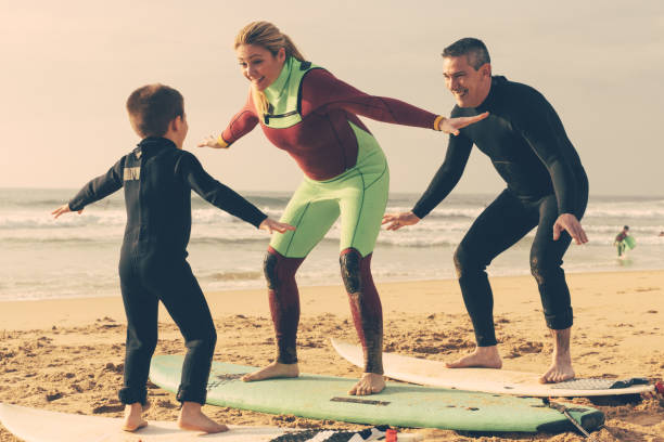 istock Family sanding on surfboards on beach 1221800264