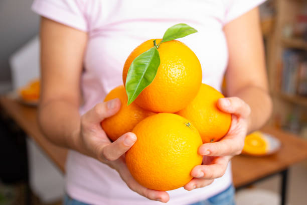 istock Young woman holding four oranges in both hands 1221801872