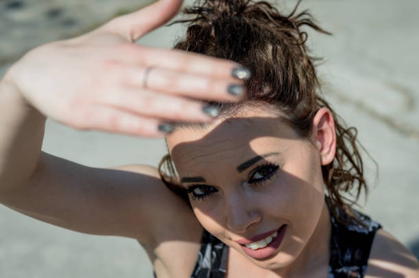 Sunlight hand protection. Young woman covering with hand's shadow the eyes to avoid sunlight. Focus on the face.