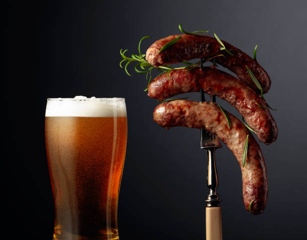 beer and grilled bavarian sausages with rosemary. sausages on a fork sprinkled with rosemary. - sausage bratwurst barbecue grill barbecue imagens e fotografias de stock