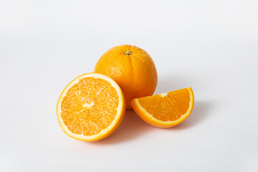 Whole orange fruit and cut segment and half isolated on white background. Closeup shot. Natural vitamin or organic food concept