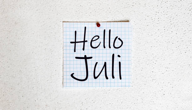 istock Hello July written on a chalkboard with a wood wall background 1221803952