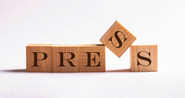 istock Five wooden cube blocks with the text press on a newspaper background 1221804948