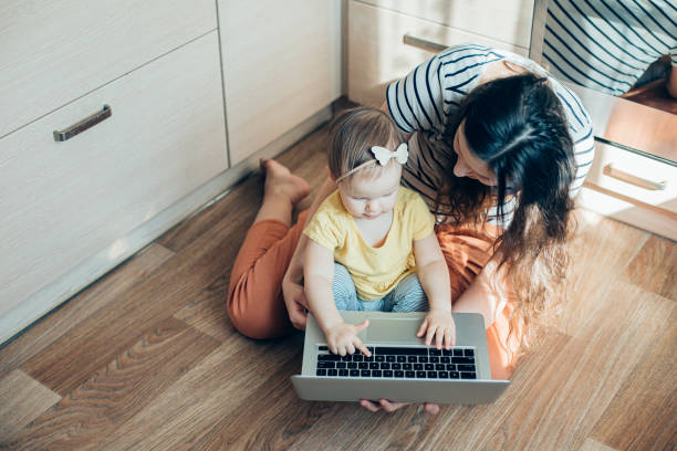 istock Inquisitive kid using laptop while sitting with mother stock photo 1221805424
