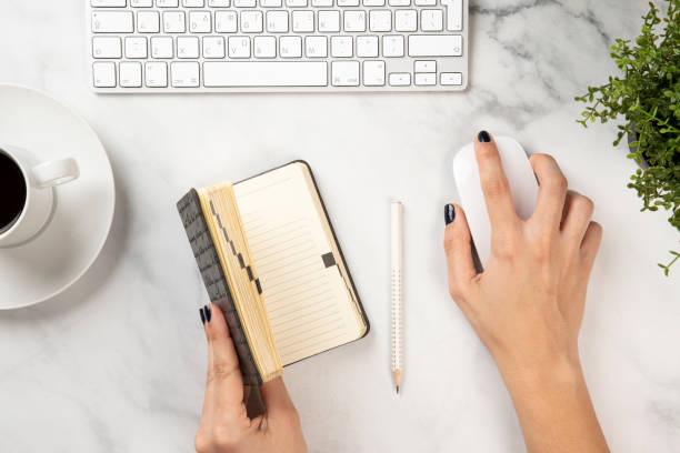 istock A woman holds the diary and the mouse on a white marble texture 1221805692