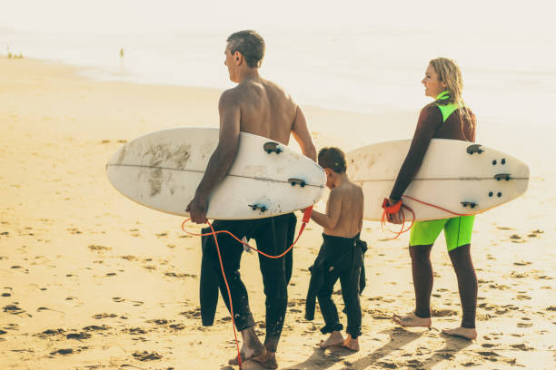 istock Family with surfboards walking on sea coast 1221808475