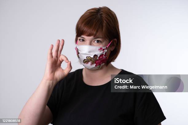 Young Red Haired Woman Putting On Self Made Face Mask With Rose Pattern Stock Photo - Download Image Now