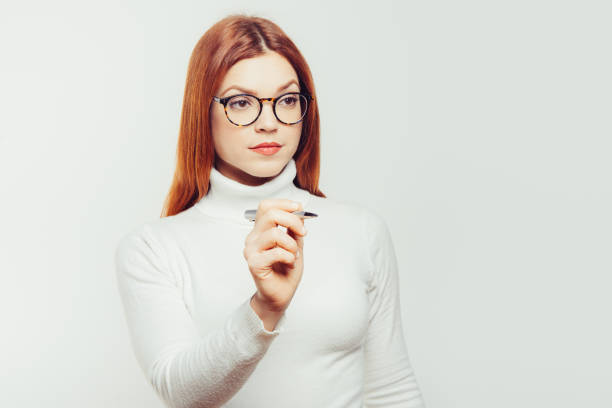 Lovely sweet business woman elegant clothing nerdy glasses holding red fake lips on stick having fun, pointing up with finger at copy space, on blue. Carnival funny accessories concept.