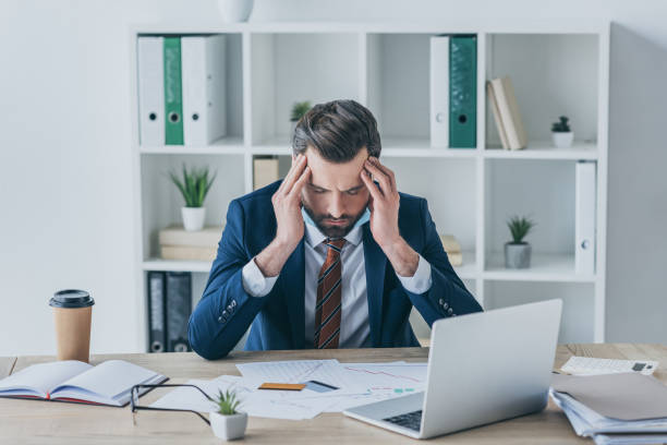 istock depressed businessman touching bowed head while sitting with closed eyes at workplace 1221811729