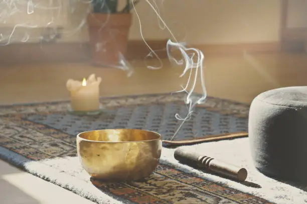 meditation room with singing bowl, incense stick, smoke, pillow and candle