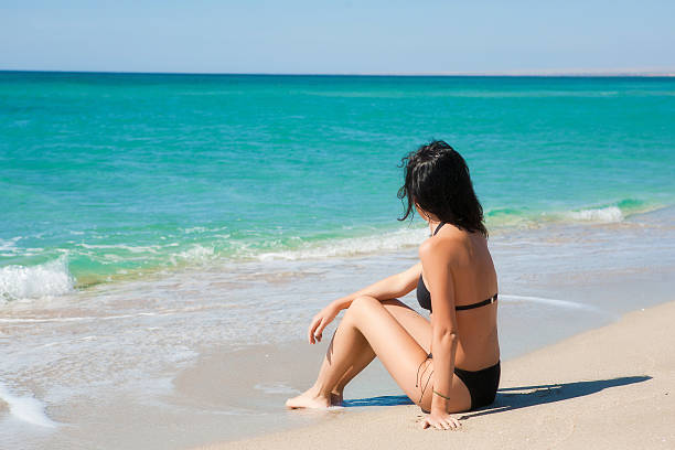 Beautiful girl sitting on the sand stock photo