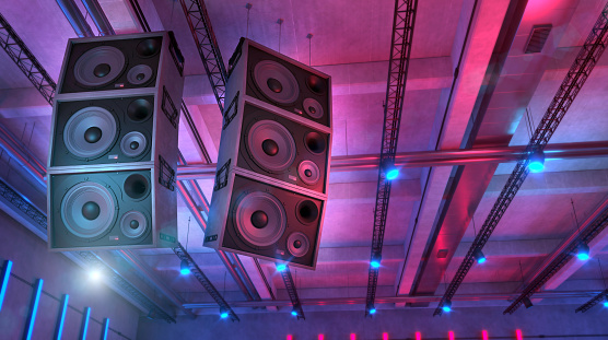Loudspeakers hanging in an live music club illuminated by blue and magenta lights. Underground club with concrete structure. Punk and rock music background. Powerful sound system and audio equipment. Digitally generated image.
