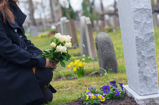 Woman visiting a grave with flowers