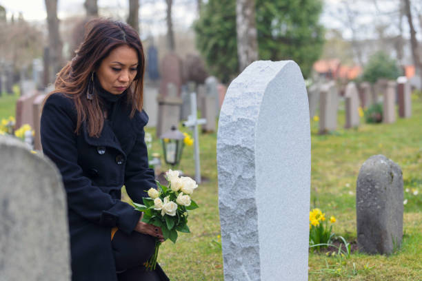 istock Woman visiting a grave at the cemetery 1221816143