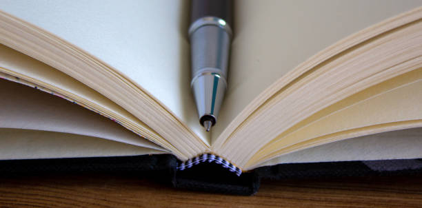 istock Open notebook and black beautiful pen on wood table. 1221820697
