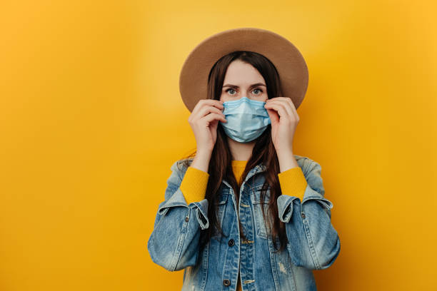 Dissatisfied woman in hat protects face with mask, thinks abot risk of epidemic disease, has virus infection, looks sadly at camera. Concept health and safety, N1H1 coronavirus, virus protection mujer insatisfecha en el sombrero protege la cara con la máscara, piensa que el riesgo de abot de enfermedad epidémica, tiene infección por virus, mira tristemente a la cámara. concepto de salud y seguridad, coronavirus n1h1, protección antivirus